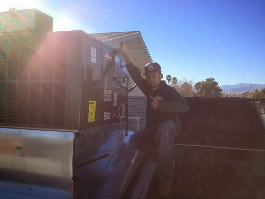 HVAC technician performing AC Tune-Up on a rooftop unit in Rainsville